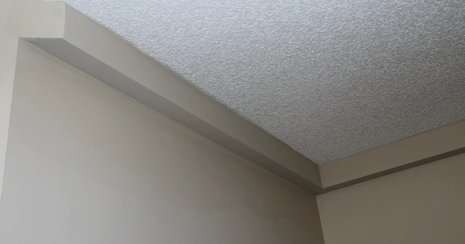 Finished track corner beneath an intact textured ceiling